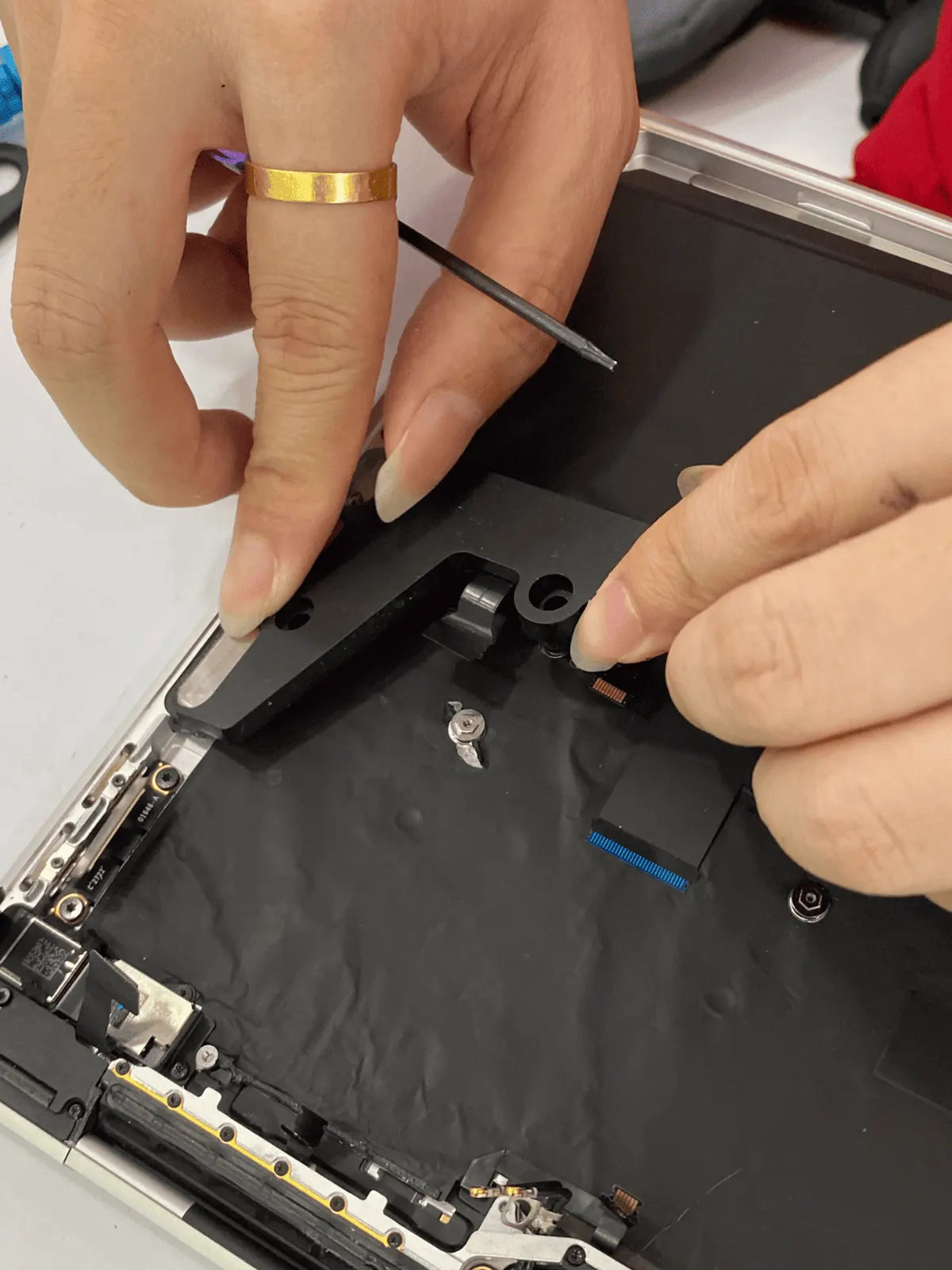 Internal bracket and ribbon cables lifted during a MacBook strip-down