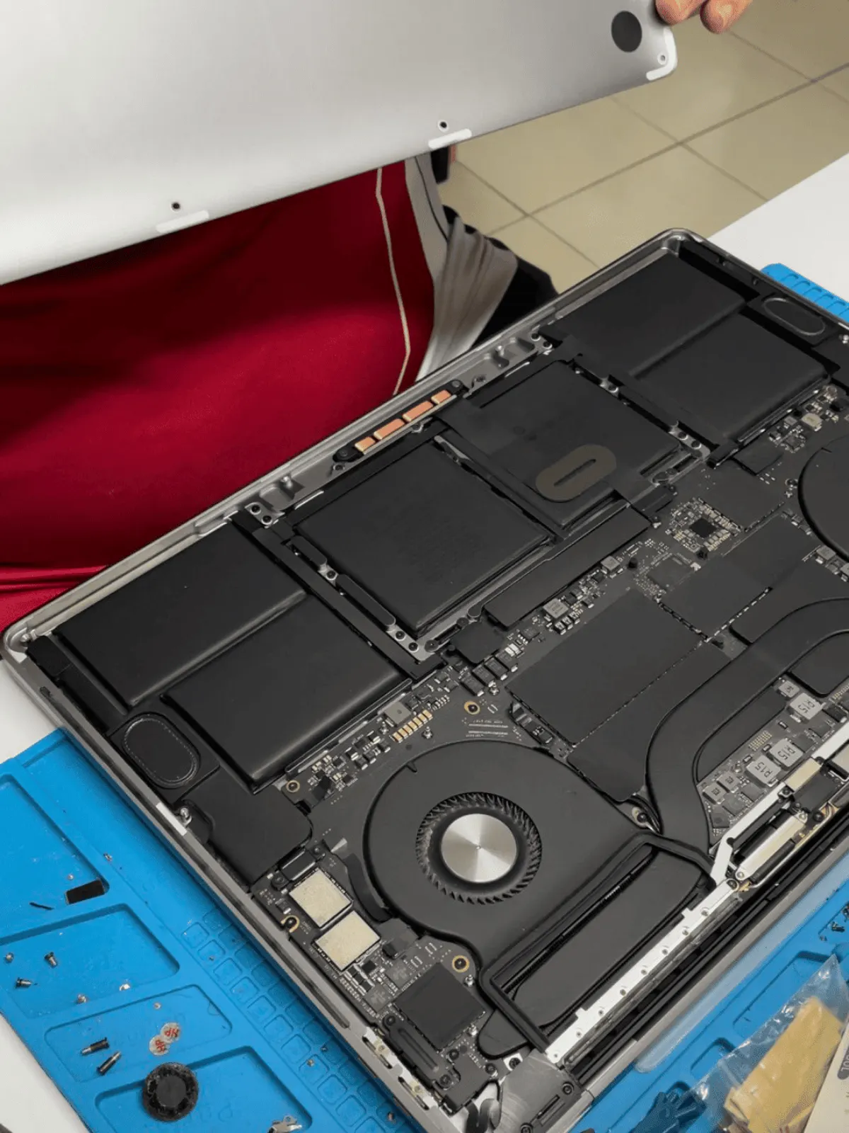 A MacBook opened on the SPR workbench with the battery and logic board exposed